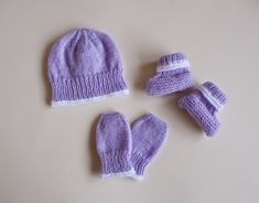 three knitted baby hats and mittens laid out on a table