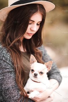 a woman in a hat holding a small dog