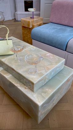 three wine glasses sitting on top of a marble coffee table in front of a couch