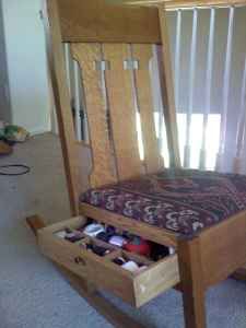 a wooden rocking chair with an open drawer underneath it