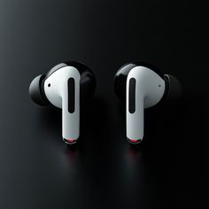 two black and white earbuds sitting next to each other on a dark surface