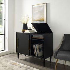 an open laptop computer sitting on top of a black cabinet next to a gray chair