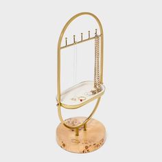 a gold and glass stand with an object on it's side, in front of a white background