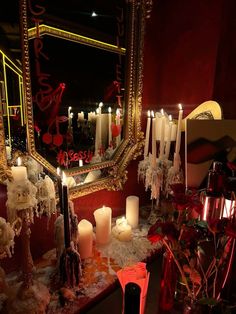 candles are lit in front of a mirror with red and white decorations on it,