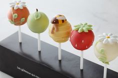 four lollipops in the shape of fruits and vegetables with flowers on them