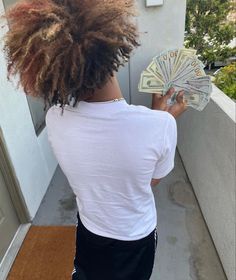 a woman with dreadlocks is holding money in her hand and looking at it