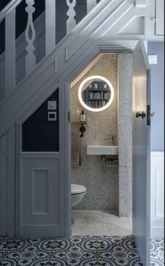 an open door leading to a bathroom with a sink and toilet under the stair case