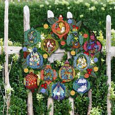 a wooden fence with a wreath made out of plates on it's side and surrounded by bushes