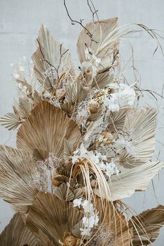 an arrangement of dried flowers and leaves in a vase