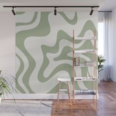 a green and white wall mural in a living room with wooden flooring, bookshelf and plant