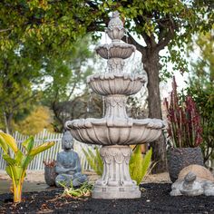 an outdoor fountain with buddha statues in the foreground and trees in the back ground