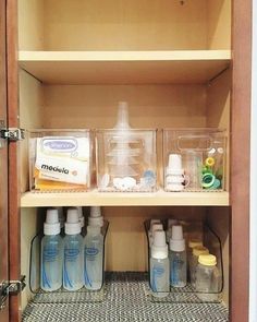 an open cabinet with bottles and containers on the bottom shelf next to other items in plastic containers