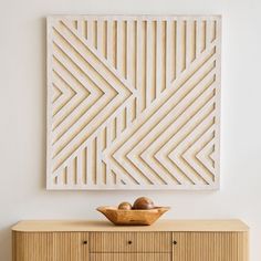 a wooden bowl sitting on top of a dresser next to a wall hanging above it