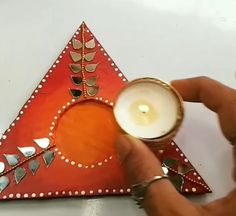 a person holding a candle in front of a triangle shaped object