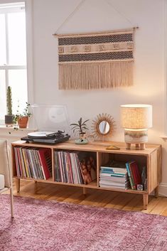 a room with a book shelf, record player and lamp on the side table in front of it