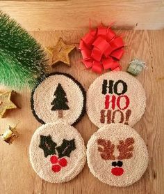 three christmas coasters on a wooden table next to a green tree and other holiday decorations