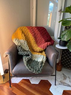 a chair with a blanket on top of it in front of a potted plant