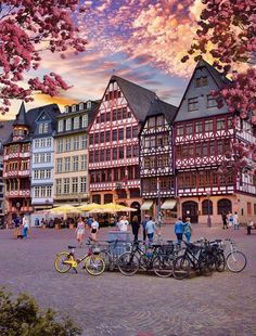 several bicycles parked next to each other in front of buildings with pink flowers on them