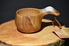 a wooden bowl sitting on top of a piece of wood next to a tag with a white handle