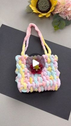 a crocheted purse sitting on top of a table next to a sunflower