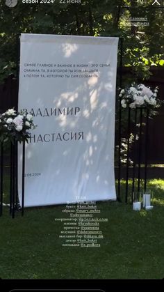 an outdoor ceremony with white flowers and black metal poles in front of a large sign