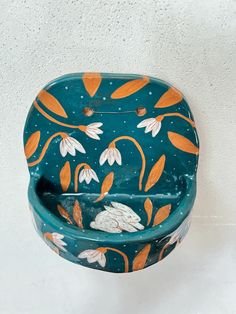 a blue toilet with orange and white flowers painted on it