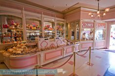 the inside of a candy shop with pink walls and gold trimmings on the windows