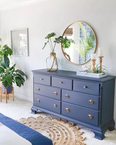 a blue dresser in a white bedroom with potted plants