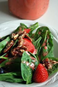 a salad with spinach, strawberries and walnuts on it is sitting on a plate