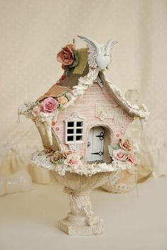 a bird house with roses and an angel on top