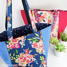 two colorful bags sitting next to each other on top of a white table with succulents in the background