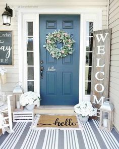 a blue front door with a welcome mat and wreath