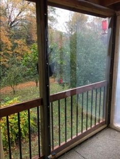 an empty balcony with sliding glass doors leading to a wooded area in the fall time