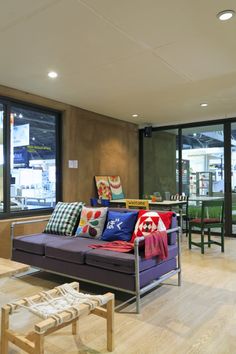 a living room filled with lots of furniture next to large windows and wooden flooring