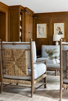 two chairs and a table in a room with wood paneling on the wall behind them