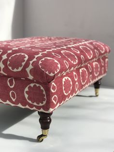 an upholstered footstool with red and white designs on it's legs