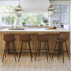 a kitchen island with three bar stools next to it