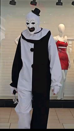 a man in a white and black costume walking past mannequins