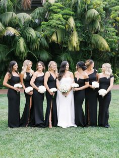 a group of women standing next to each other on top of a lush green field