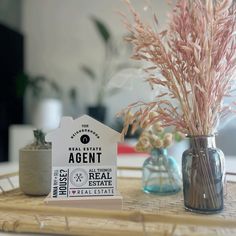 there is a vase with some flowers in it on the table next to a real estate sign