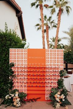 an orange and white wedding ceremony backdrop with palm trees in the backgroung