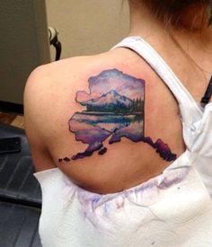 a woman's back shoulder with a watercolor map tattoo on her upper arm