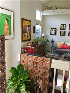 a living room filled with furniture and pictures on the wall next to a potted plant