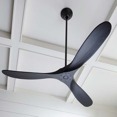 a black ceiling fan hanging from the ceiling in a room with white walls and ceilings