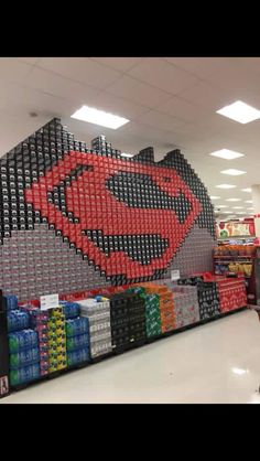 a display in a store filled with lots of soda cans and superman logo on the wall