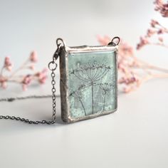 "Keep the nature close to your heart wherever you are. This is a hand painted Queen Anne's Lace flower pendant in a unique green-gray color.  Waste window glass gets a new life as pieces of art to wear. Perfect sustainable gift for someone you care about, that care about the environment. The two lobster clasps make it a thoughtful gift for someone with weakness in hands and arms, it's easy to put on from the front, in addition to just being cool and different. Two functionalities in one item! Wh Nature-inspired Hand Painted Necklace For Gift, Hand Painted Nature-inspired Necklace For Gift, Green Hand Painted Necklace For Gift, Green Handmade Necklace For Keepsake, Green Necklace With Natural Inclusions For Gift, Green Botanical Necklace Perfect For Gifting, Green Botanical Necklace For Gift, Green Botanical Necklace For Gifts, Green Botanical Style Necklace For Gift