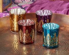 three different colored glass cups sitting on top of a metal tray next to a purple blanket