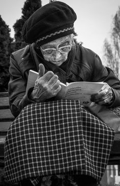 an old woman sitting on a bench reading a book