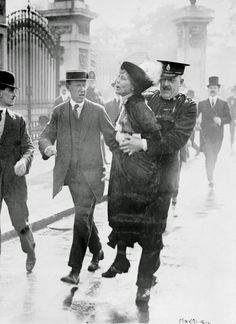 an old black and white photo of people walking in the rain with hats on their heads