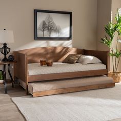 a day bed sitting on top of a white rug next to a table with a potted plant